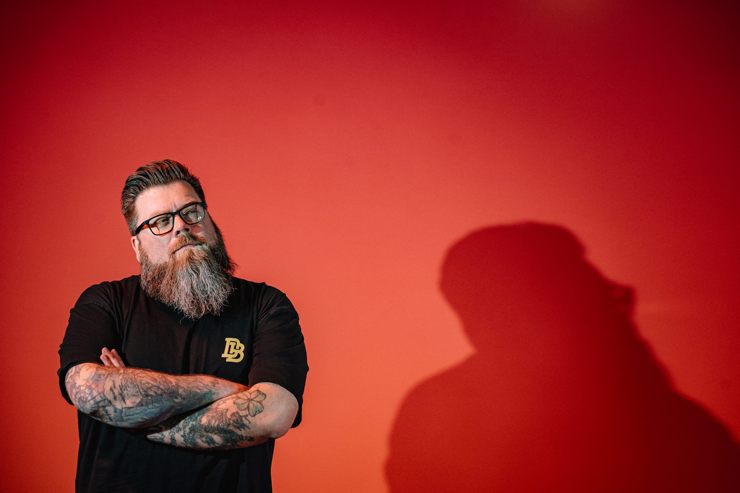 Bennett Newsome, arms crossed, against a red wall